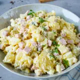 Ein Teller mit Omas Kartoffelsalat mit Mayonnaise, garniert mit Petersilie. Ein Klassiker, der immer schmeckt!