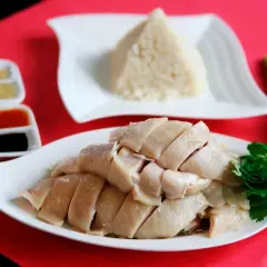 Zartes, geschnittenes Hähnchenfleisch mit duftendem Reis und Soßen – ein klassisches Hainanese Chicken Rice Gericht.