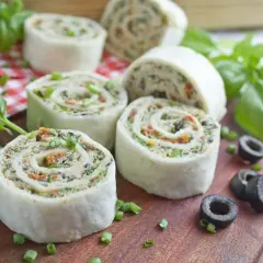 Italienische Antipasti Fingerfood-Röllchen mit Oliven und Basilikum auf Holzbrett.