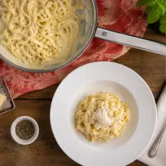 Cremige Pasta Alfredo, zubereitet nach einem einfachen Rezept. Serviert auf einem Teller mit frisch geriebenem Parmesan und Pfeffer.