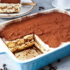 Ein köstliches Tiramisu mit Sahne und Mascarpone, bestäubt mit Kakao. Ein Stück wurde bereits entnommen.