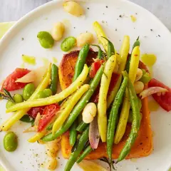 Bunte Bohnen im Backofen mit Tomaten und Lachs auf einem Teller.