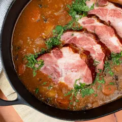 Gegarter Kassler in Scheiben in einer deftigen Soße, garniert mit Petersilie. Die Frage "wie lange braucht 1 kg Kassler im Backofen" beschäftigt viele Hobbyköche.