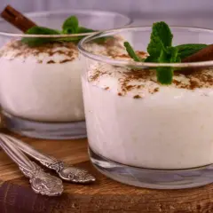 Zwei Gläser cremiger Milchreis, garniert mit Zimt und Minze. Ein einfaches Milchreis Rezept, das süße Erinnerungen weckt.
