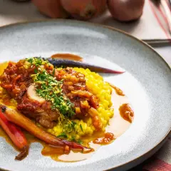 Ein köstliches Ossobuco Rezept mit zartem Kalbfleisch, serviert auf cremigem Safranrisotto und garniert mit frischen Kräutern und karamellisierten Karotten.