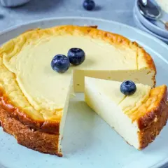 Leckerer protein cheesecake aus magerquark, garniert mit Blaubeeren. Ein Stück ist bereits angeschnitten.