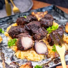 Herzhaftes Mutzbraten Rezept Original: Dunkles, saftiges Fleisch auf Sauerkraut, garniert mit Petersilie und gerösteten Zwiebeln. Ein Festmahl!