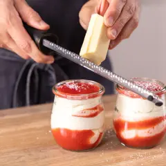 Zwei Gläser mit einem köstlichen Spaghetti Eis Dessert werden mit weißer Schokolade garniert.