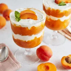 Schichtdessert mit Aprikosenpüree und Mascarponecreme, garniert mit frischen Aprikosenspalten und Minze.