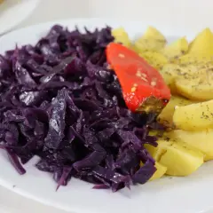 Rotkohl-Rezepte mal anders: Ein Teller mit deftigem Rotkohl, Kartoffelspalten und einer roten Paprika.