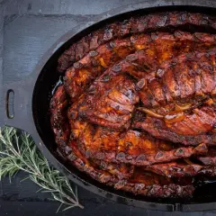 Saftige Spareribs, glasiert und geschmort im Dutch Oven, dane ein Rosmarinzweig.