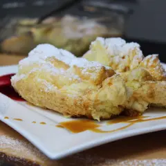 Perfekte Salzburger Nockerl, die nicht zusammenfallen, bestäubt mit Puderzucker und garniert mit Karamell und roter Sauce.