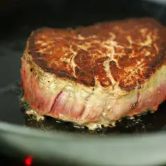 Ein saftiges Steak brät in einer Pfanne. Die Kruste ist goldbraun, das Innere noch rosa. Perfekt, um ein Steak richtig braten zu lernen.