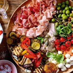 Vielfältige Antipasti Platte Ideen: Wurst, Käse, Oliven, gegrilltes Gemüse und frische Tomaten auf rustikalem Holzbrett.