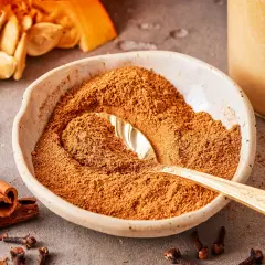 Schüssel mit Gewürzmischung zum Pumpkin Spice selber machen, daneben Zimtstangen, Nelken und Kürbiskerne.
