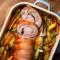 Saftiger **Rollbraten im Backofen** mit Rosmarinkartoffeln und Karotten, bereit zum Servieren.