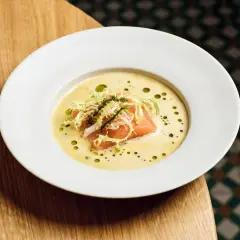 Ein Teller mit Lachs auf cremigem beurre blanc, garniert mit Salat und Kaviar.