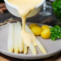 Weißer Spargel mit kleinen Kartoffeln und Petersilie, übergossen mit cremiger Sauce Hollandaise.
