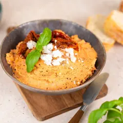 Ein cremiger Tomaten Feta Dip, garniert mit getrockneten Tomaten und Basilikum. Perfekt zum Dippen mit Brot.