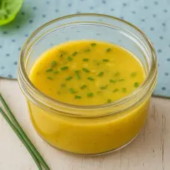 Ein Glas mit leckerem Honig-Senf-Dressing, garniert mit Schnittlauch. Perfekt für dein nächstes Salat-Rezept!