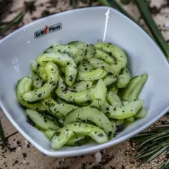 Frischer gurkensalat mit dill, garniert mit Pfeffer und Kräutern, serviert in einer weißen Schüssel.
