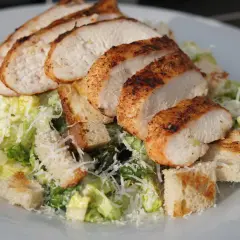 Saftiges Hähnchenbrustfilet auf knackigem Salat mit Croutons und Parmesan – ein klassischer Caesar Salad.