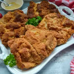 Goldbraun paniertes Schnitzel, perfekt zubereitet. Dazu Radieschen und Senf. Ein Genuss für jeden, der gerne Schnitzel paniert.