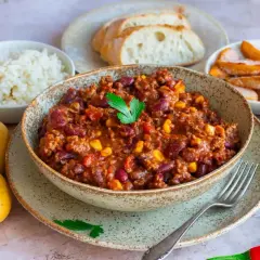 Herzhaftes Chili con Carne als Beilage, serviert mit Reis, Brot, Kartoffeln und Nudeln. Ein Festmahl!