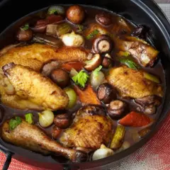 Coq au Riesling rezept original: Ein ganzer Brathähnchen-Mix mit Pilzen, Zwiebeln und Sellerie in dunkler Sauce.