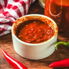 Selbstgemachte Chilipaste in einer Schale, umgeben von frischen Chilis. Perfekt, um dein Essen zu würzen!