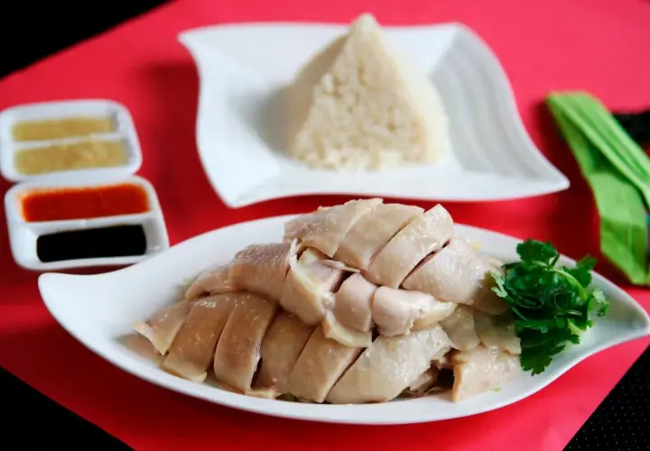 Zartes, geschnittenes Hähnchenfleisch mit duftendem Reis und Soßen – ein klassisches Hainanese Chicken Rice Gericht.