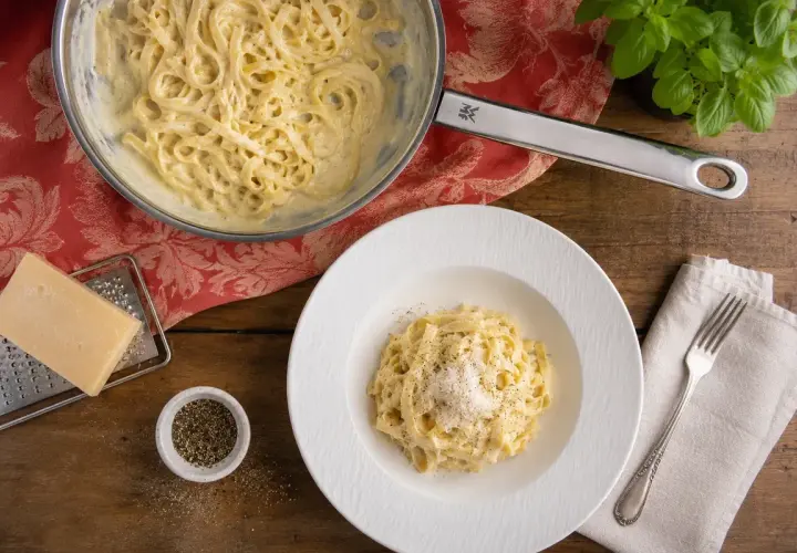 Cremige Pasta Alfredo, zubereitet nach einem einfachen Rezept. Serviert auf einem Teller mit frisch geriebenem Parmesan und Pfeffer.