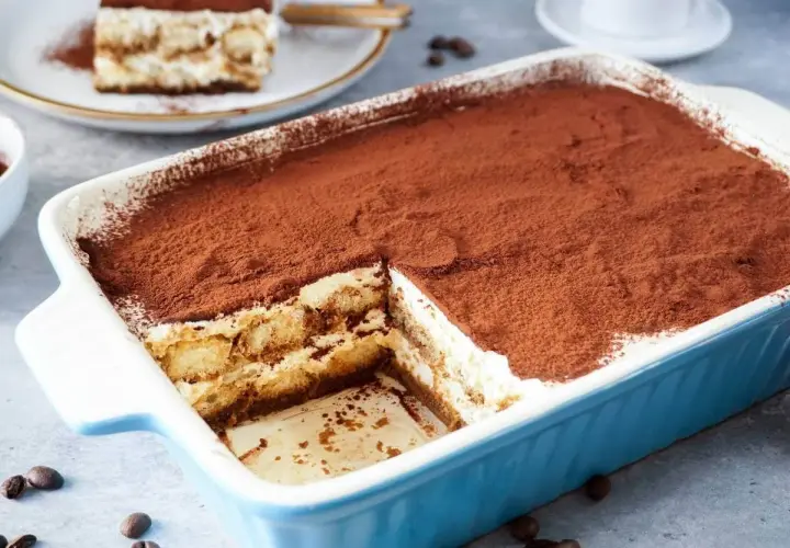 Ein köstliches Tiramisu mit Sahne und Mascarpone, bestäubt mit Kakao. Ein Stück wurde bereits entnommen.
