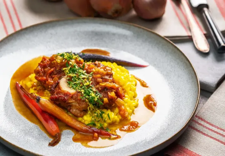 Ein köstliches Ossobuco Rezept mit zartem Kalbfleisch, serviert auf cremigem Safranrisotto und garniert mit frischen Kräutern und karamellisierten Karotten.