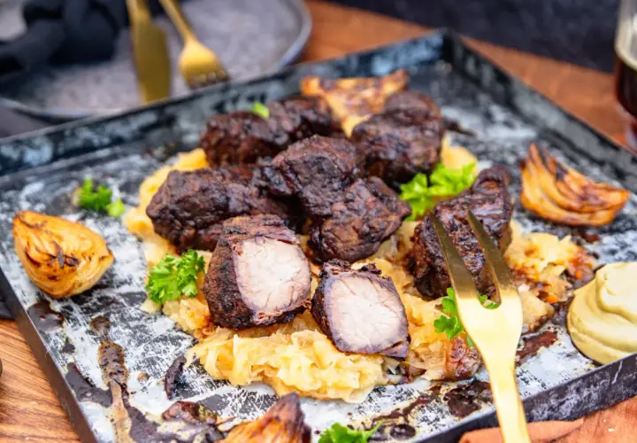 Herzhaftes Mutzbraten Rezept Original: Dunkles, saftiges Fleisch auf Sauerkraut, garniert mit Petersilie und gerösteten Zwiebeln. Ein Festmahl!