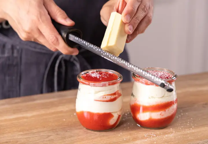 Zwei Gläser mit einem köstlichen Spaghetti Eis Dessert werden mit weißer Schokolade garniert.