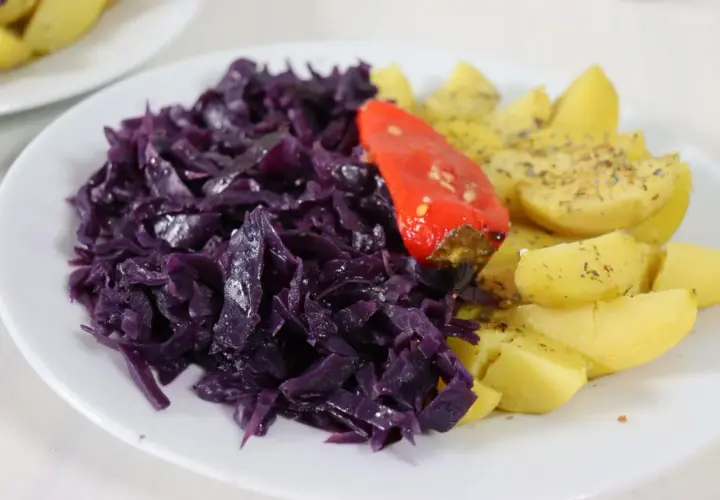 Rotkohl-Rezepte mal anders: Ein Teller mit deftigem Rotkohl, Kartoffelspalten und einer roten Paprika.
