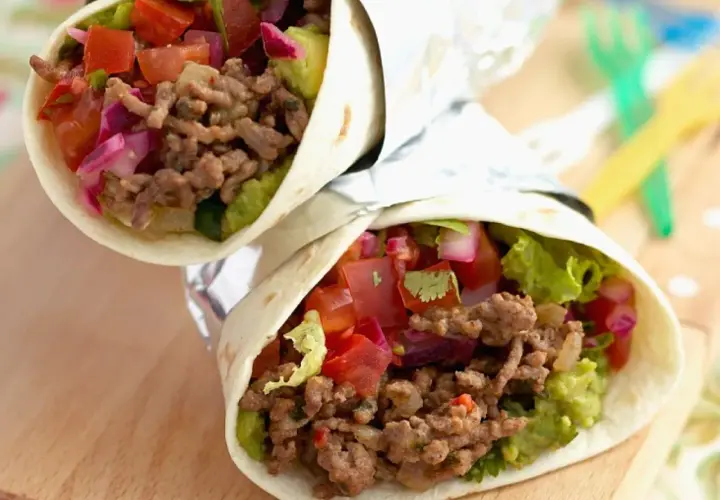 Zwei saftige wraps mit hackfleisch, Guacamole, Tomaten und roten Zwiebeln, eingewickelt in Folie.