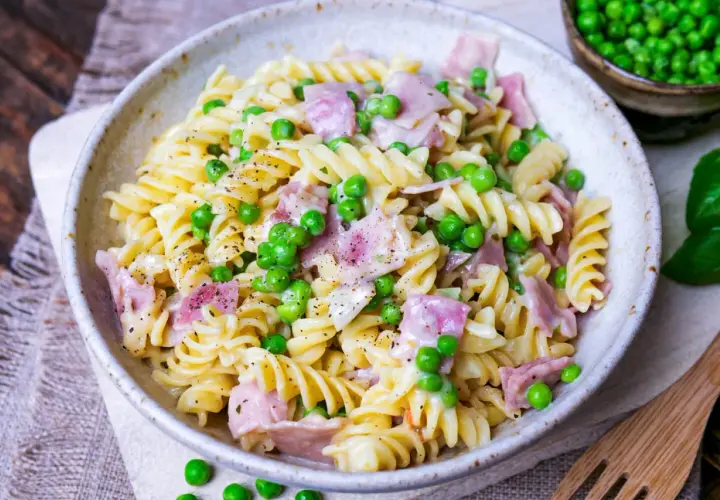 Fusilli-Nudeln mit Erbsen und Schinken in cremiger Schinken Sahne Sauce, bestreut mit schwarzem Pfeffer.