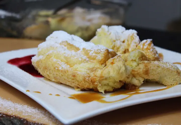 Perfekte Salzburger Nockerl, die nicht zusammenfallen, bestäubt mit Puderzucker und garniert mit Karamell und roter Sauce.