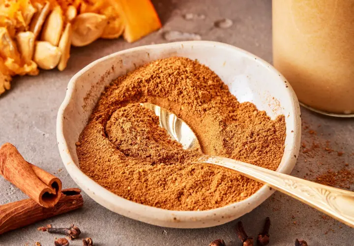 Schüssel mit Gewürzmischung zum Pumpkin Spice selber machen, daneben Zimtstangen, Nelken und Kürbiskerne.