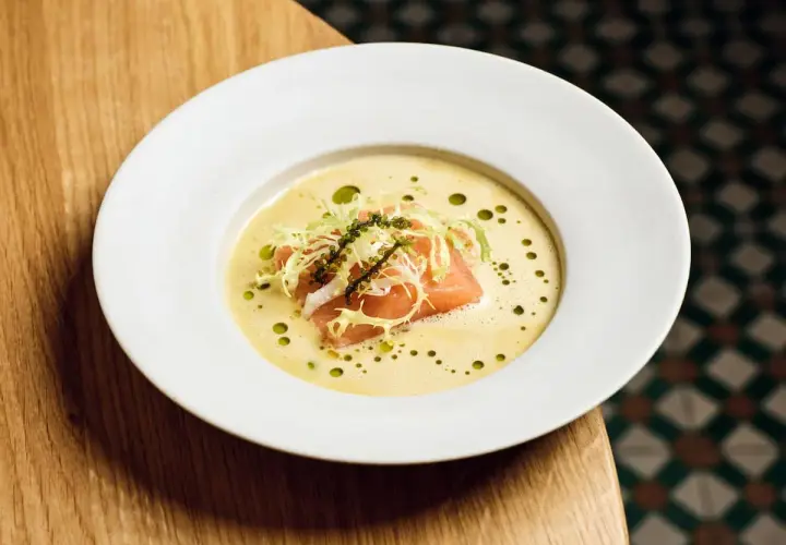 Ein Teller mit Lachs auf cremigem beurre blanc, garniert mit Salat und Kaviar.