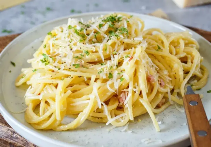 Ein Teller cremiger Spaghetti Carbonara, garniert mit Parmesan und Petersilie. Perfekt für einfache spaghetti rezepte.