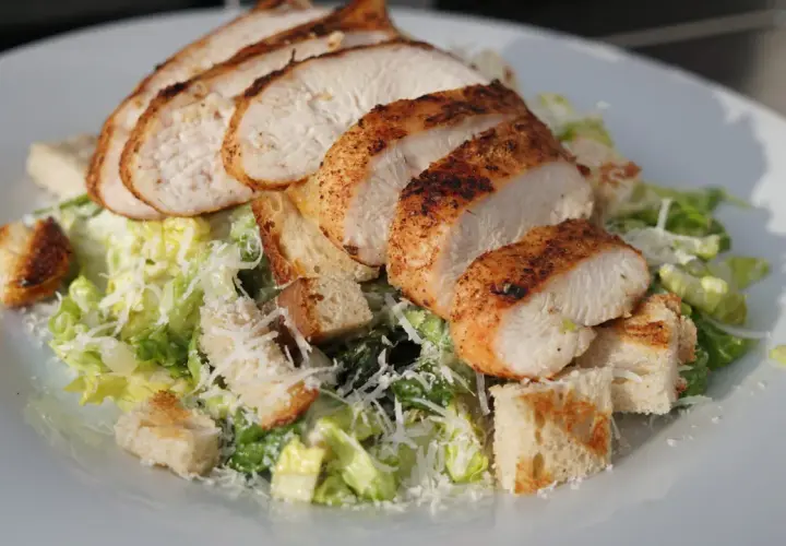 Saftiges Hähnchenbrustfilet auf knackigem Salat mit Croutons und Parmesan – ein klassischer Caesar Salad.