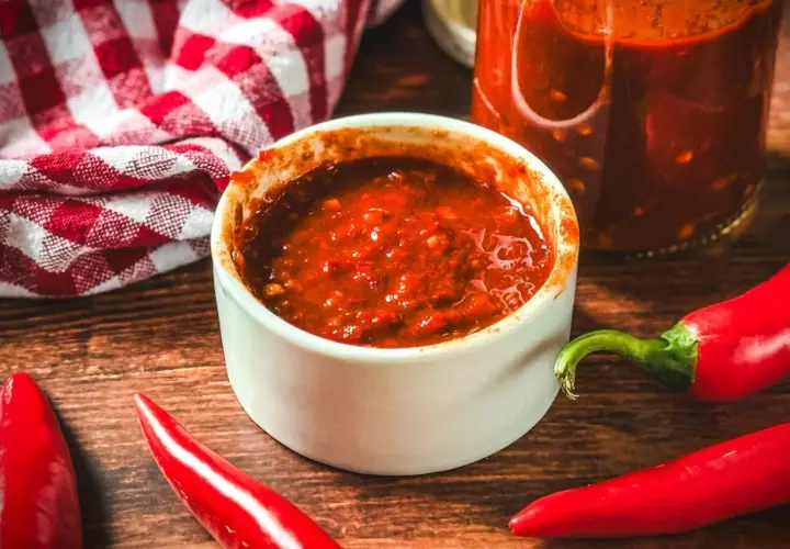 Selbstgemachte Chilipaste in einer Schale, umgeben von frischen Chilis. Perfekt, um dein Essen zu würzen!