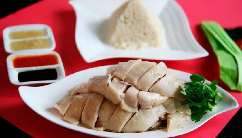 Zartes, geschnittenes Hähnchenfleisch mit duftendem Reis und Soßen – ein klassisches Hainanese Chicken Rice Gericht.