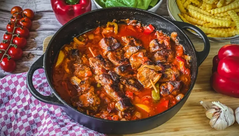 Herzhafter Schaschlik im Ofen ohne Anbraten, geschmort in Tomatensoße mit Paprika und Zwiebeln. Dazu Pommes und frische Tomaten.