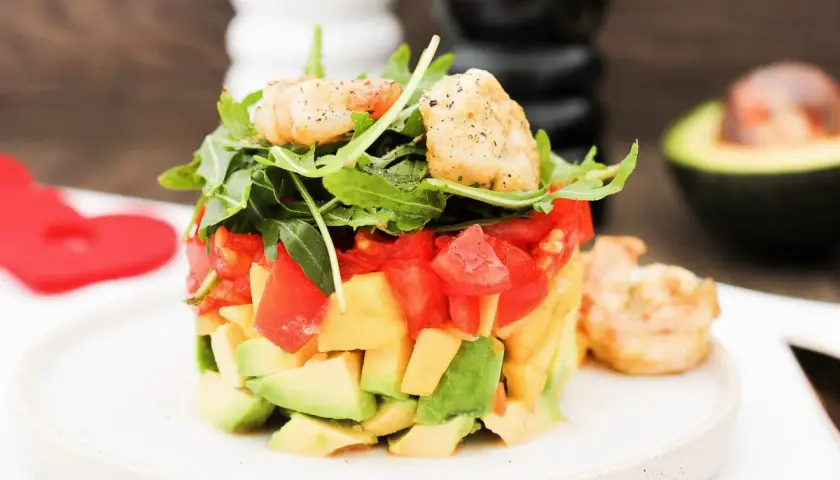 Ein sommerlicher Salat mit Garnelen, Avocado und Tomaten, garniert mit Rucola. Perfekt für heiße Tage!