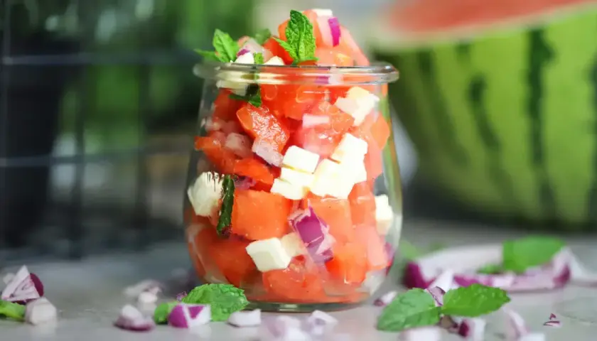 Erfrischender Wassermelonen Salat mit Feta, roten Zwiebeln und Minze in einem Glas. Perfekt für heiße Tage!