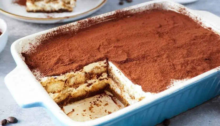Ein köstliches Tiramisu mit Sahne und Mascarpone, bestäubt mit Kakao. Ein Stück wurde bereits entnommen.